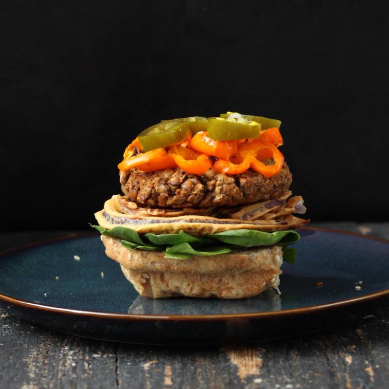 loaded vegan lentil burger without the bun top on a blue plate