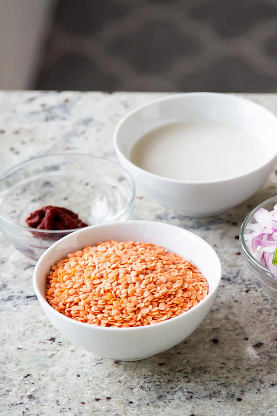 split red lentils in a bowl with other ingredients around it