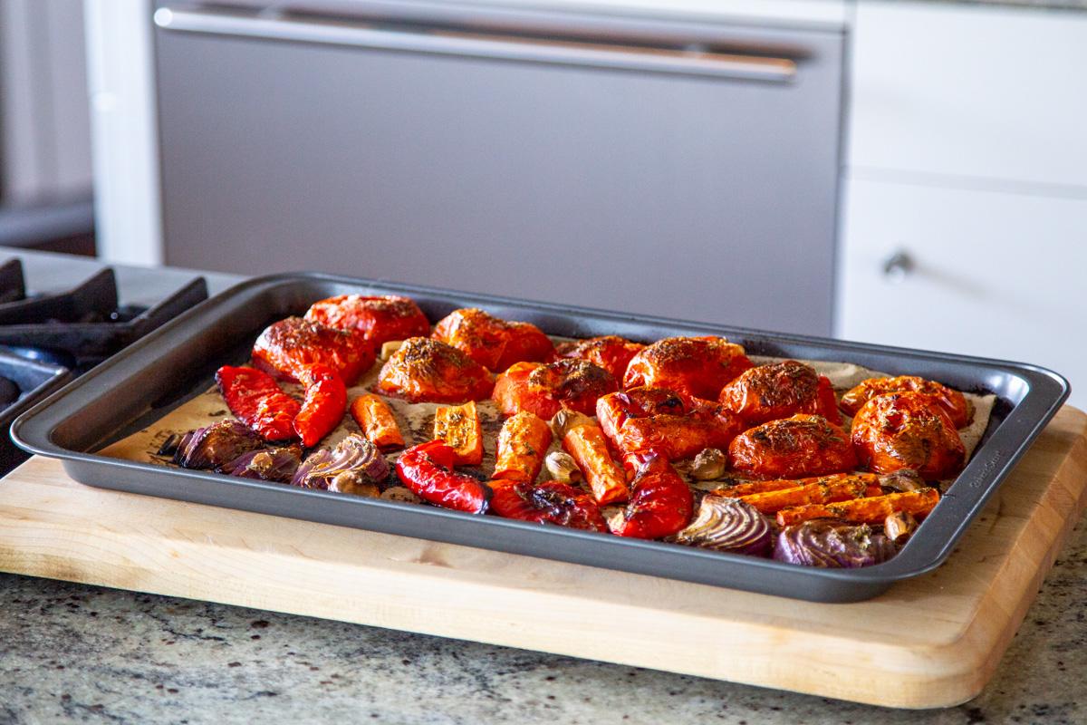 roasted bell peppers, tomatoes, garlic and onions on a baking sheet