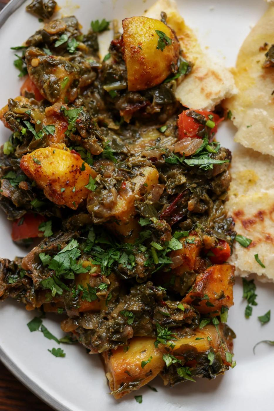 saag aloo on the plate with flatbread on the side