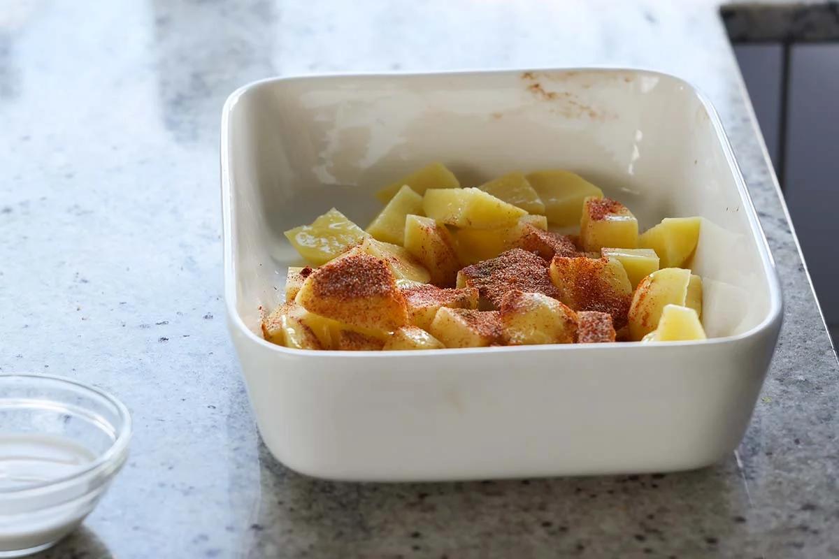 sprinkling spices onto the potatoes