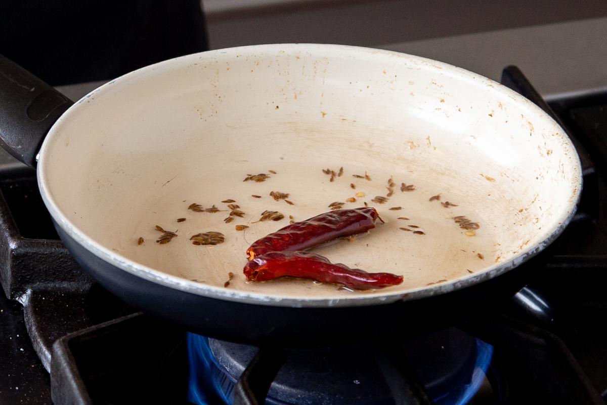 cumin seeds and chili in a frying pan