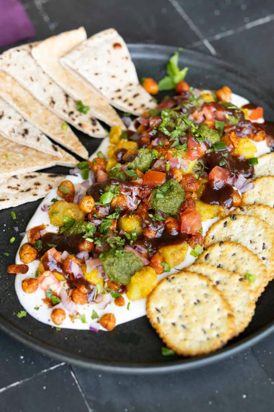 samosa platter with yogurt bed on a Black plate