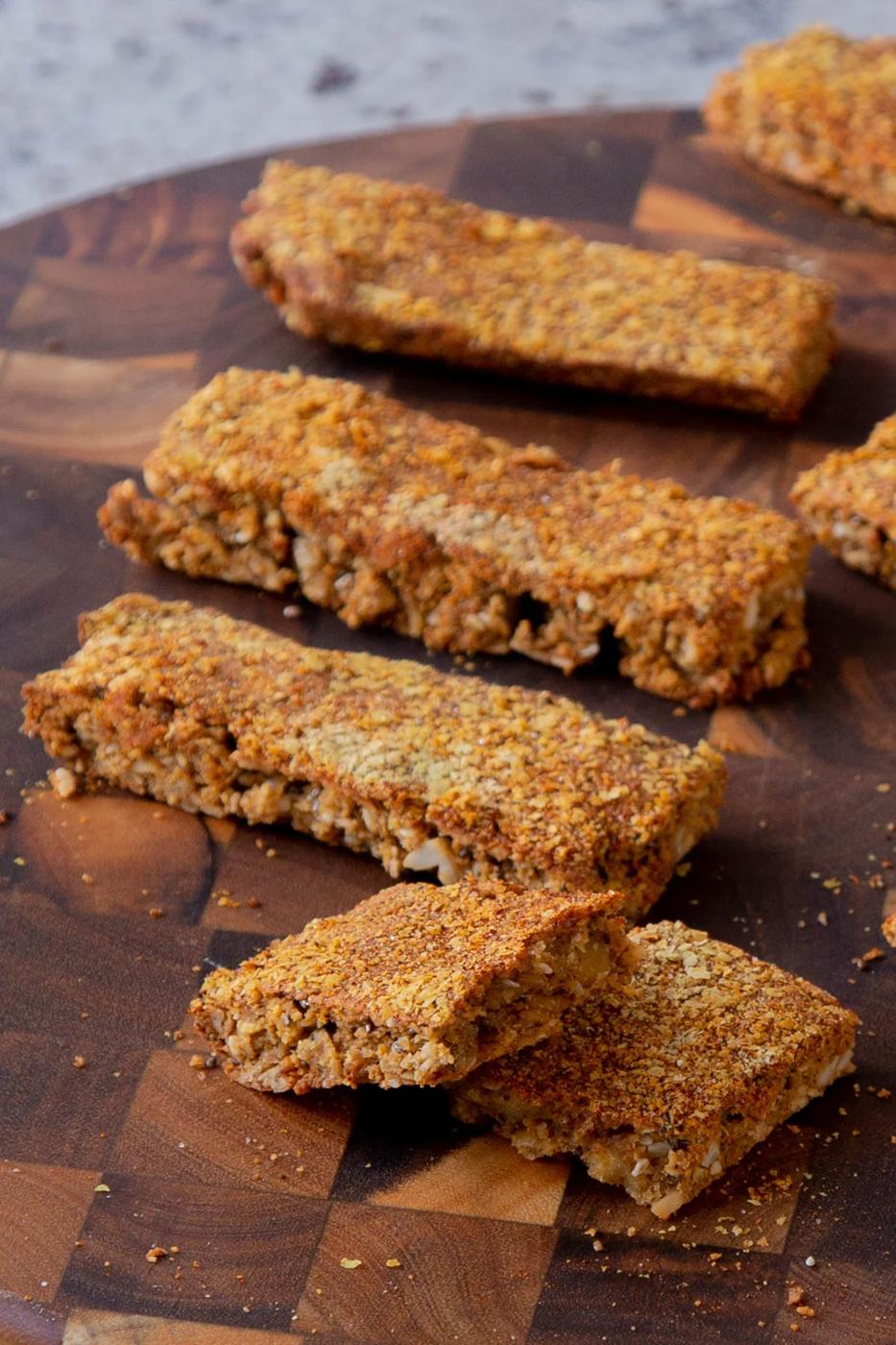 savory granola bars on a cutting board, one is broken in half so you can see the texture inside