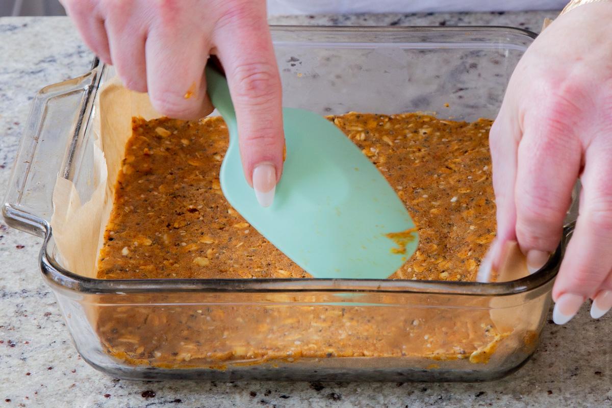 pressing the savory granola bar dough into the lined baking pan