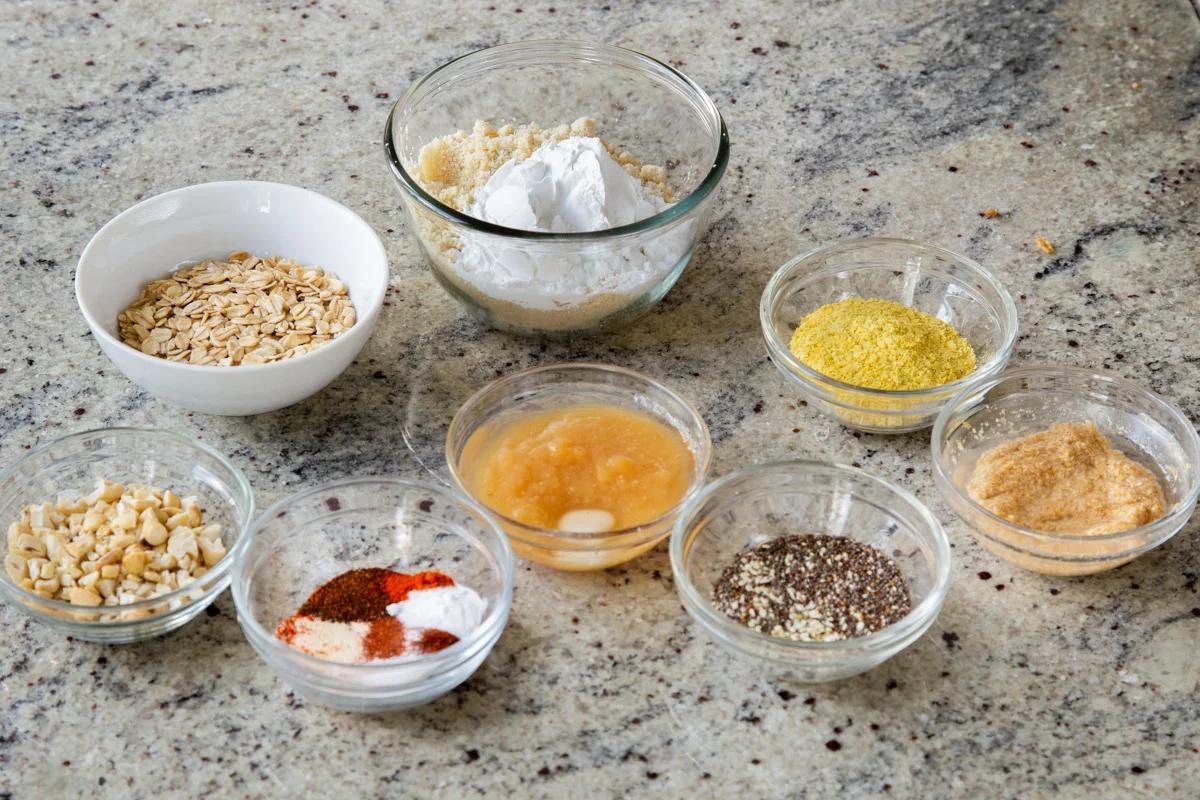 oats, almond flour, and other ingredients in bowls on a kitchen counter