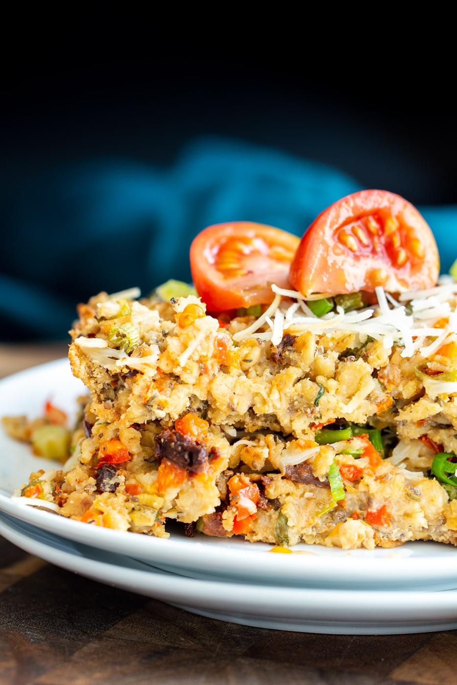 a slice of savory pizza oatmeal bake topped with vegan mozzarella and tomatoes