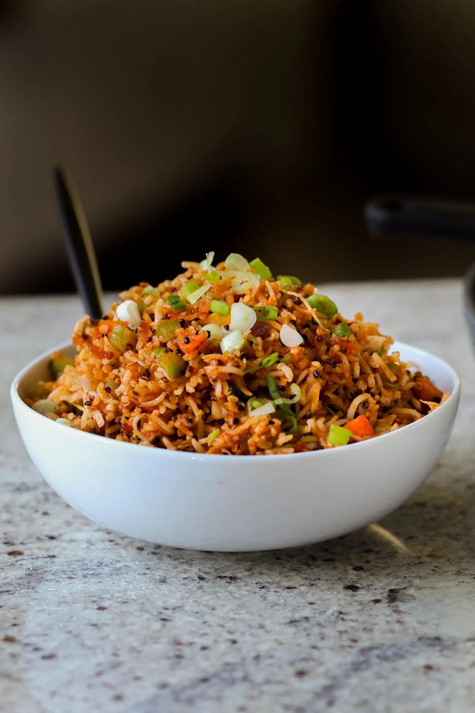 Schezwan fried rice in a bowl with green onions for garnish