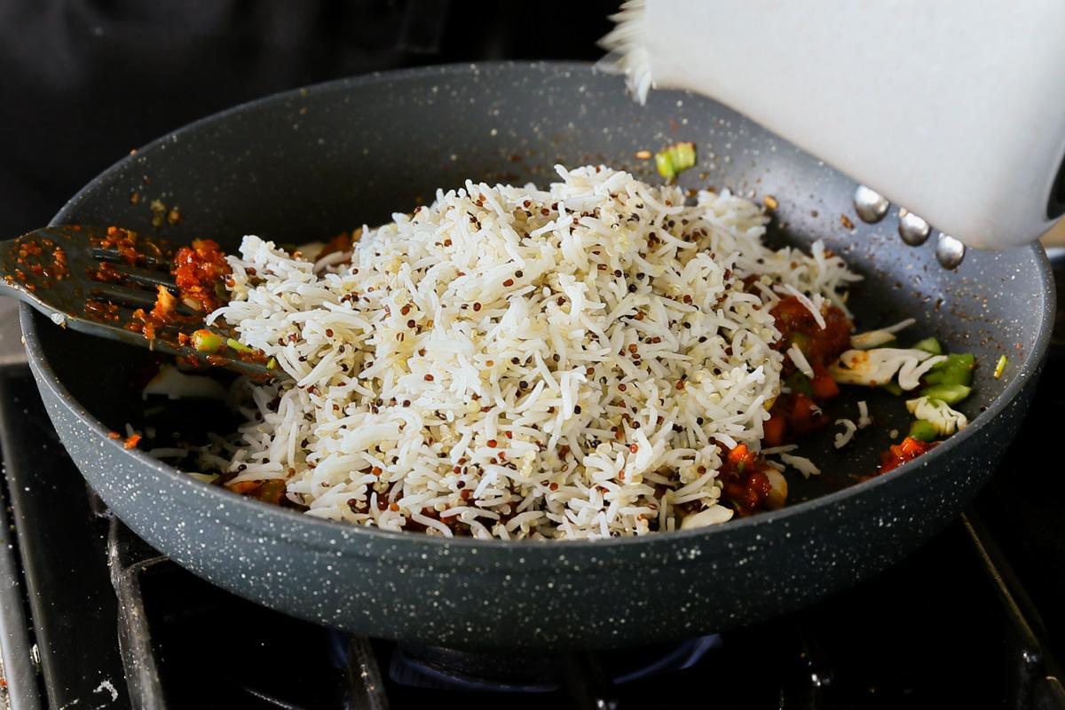 adding rice mixture to the Schezwan sauce and veggies in the pan