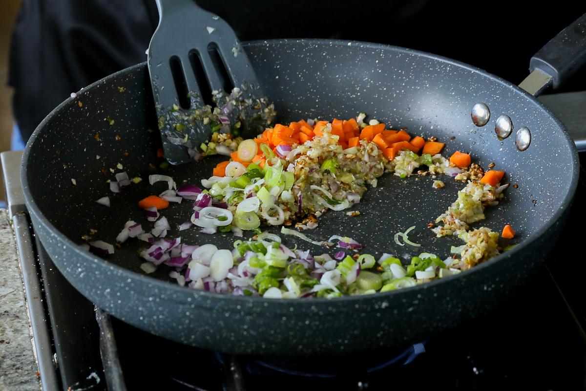 adding carrots and onions to the cooked aromatics in the pan