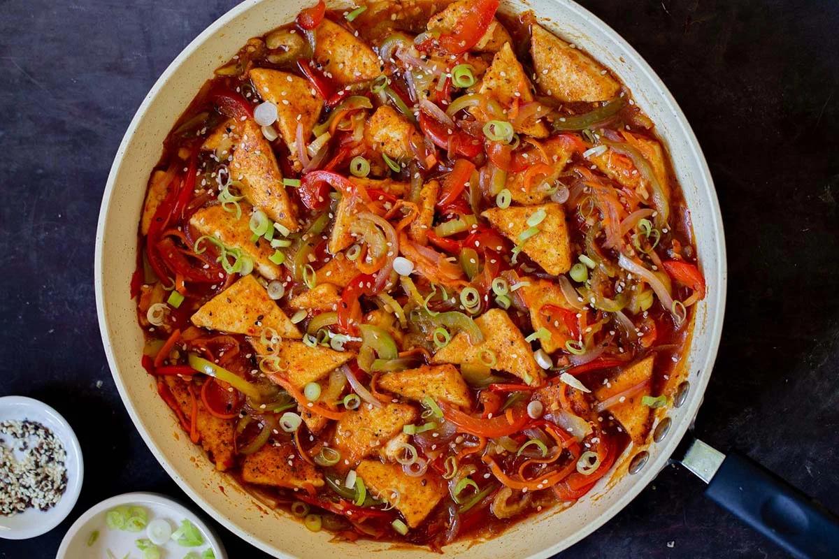 Szechuan tofu in the pan with green onions and sesame seeds