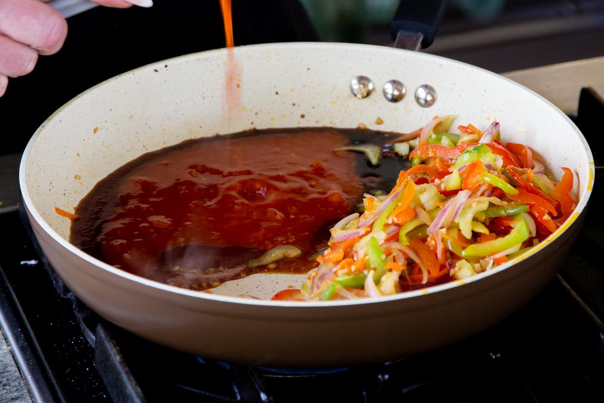 adding sauces to the pan of veggies