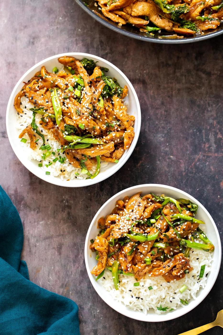 two white bowls with sesame soy curl stir-fry served alongside white rice