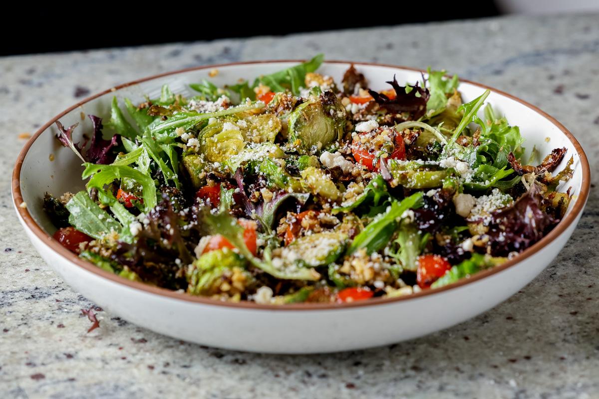 shaved Brussels sprouts salad in a bowl with tomatoes, lettuce, and walnut crumble