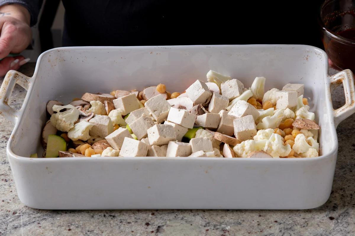 adding tofu to the pan of veggies and chickpeas