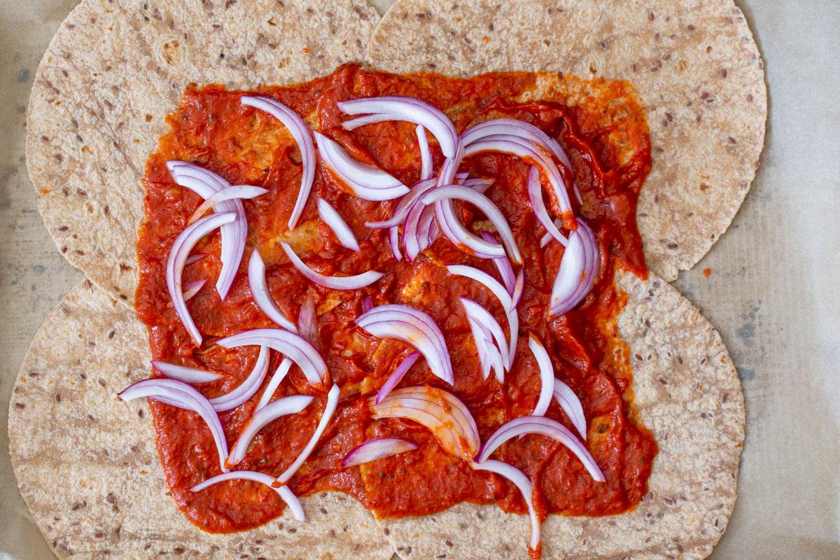 onions arranged on top of the pizza sauce