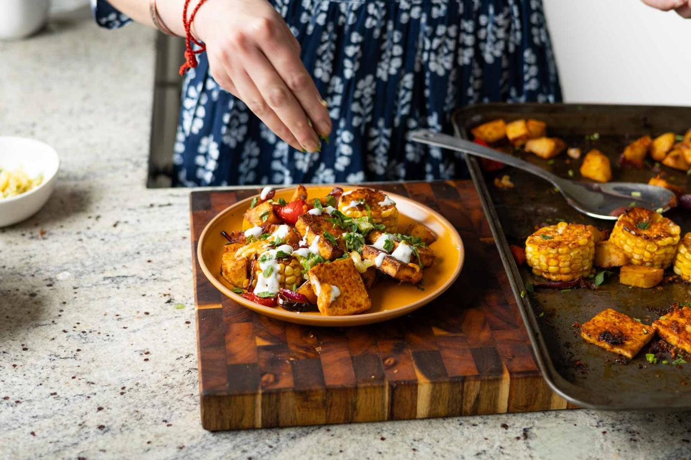 adding herbs on top of the peri-peri tofu and vegetables