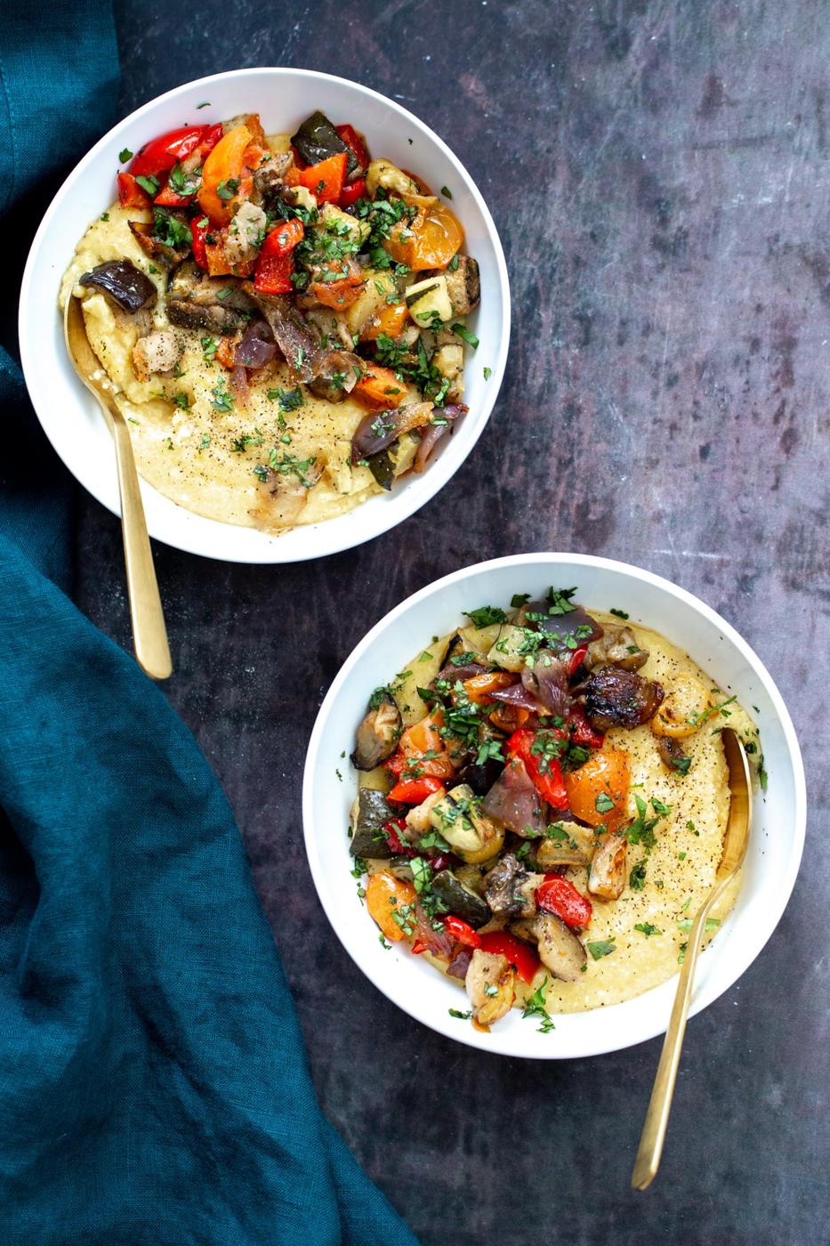 vegan sheet pan baked ratatouille served over polenta sprinkled with fresh herbs