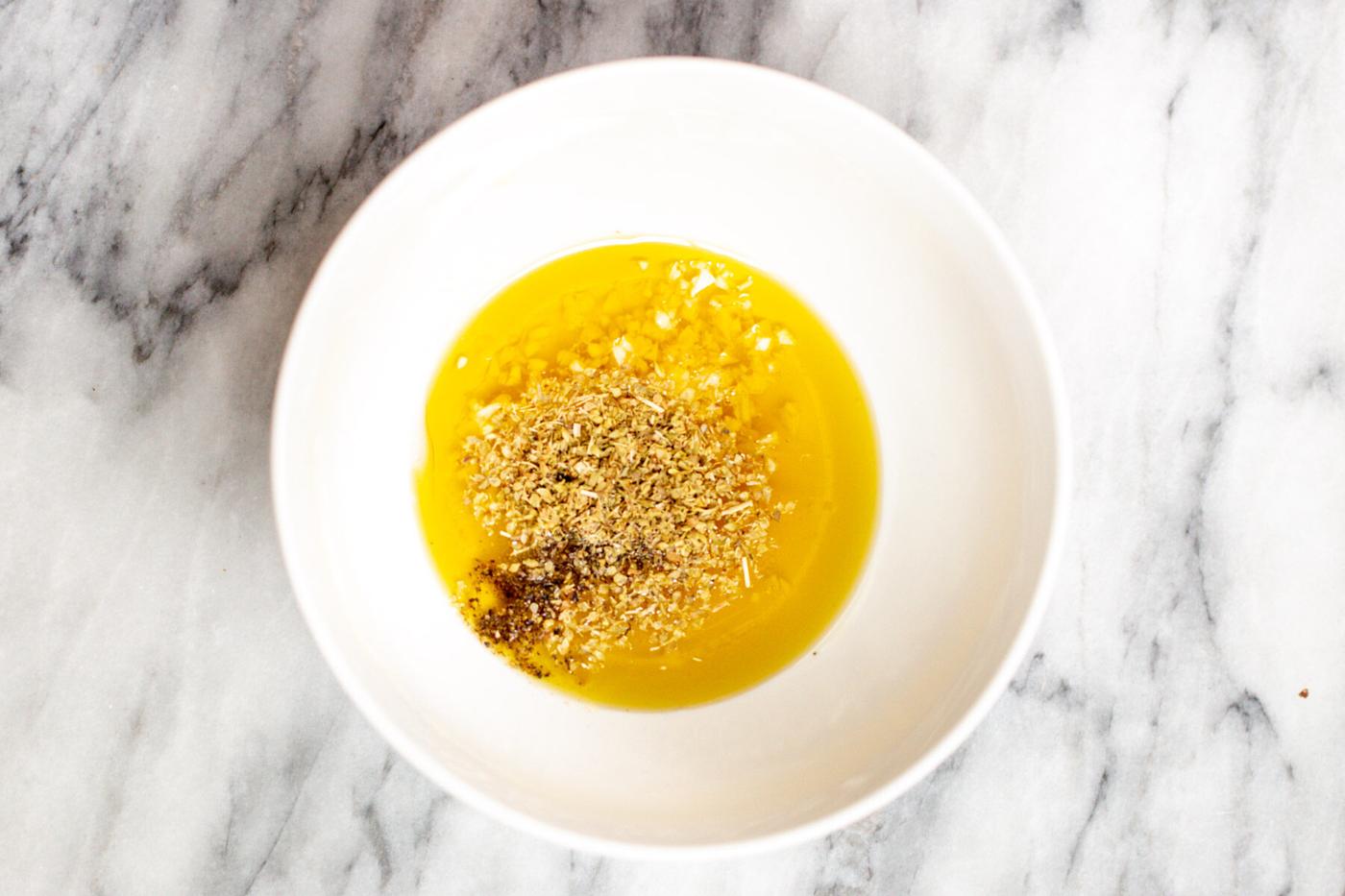 Mediterranean dressing ingredients being combined in a small white dish