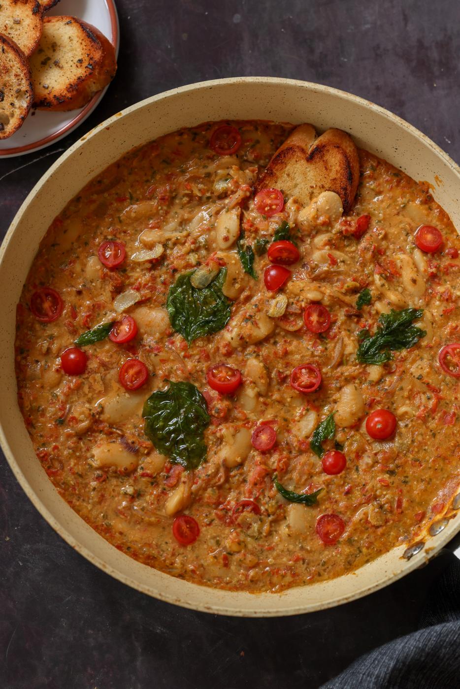 sicilian pesto sauce butter beans in the pan topped with crispy basil