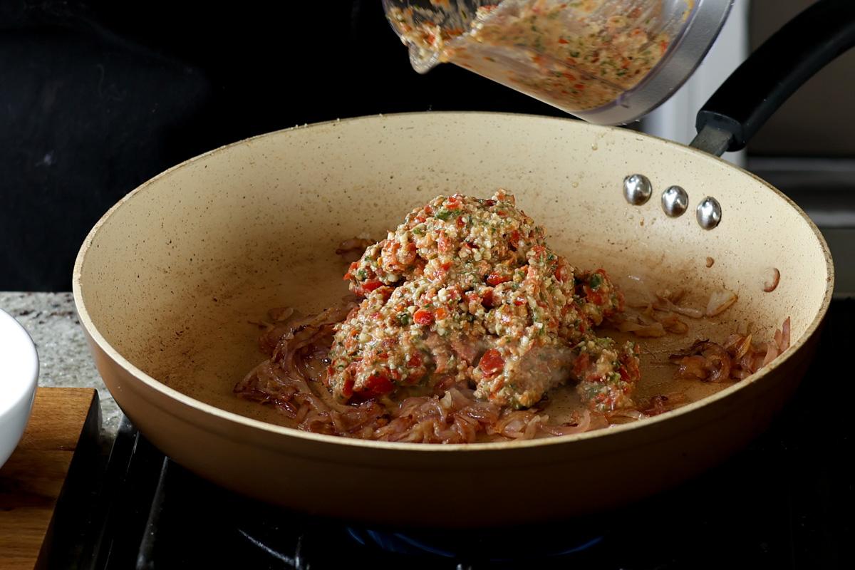 adding Sicilian pesto sauce to the pan of cooked onion