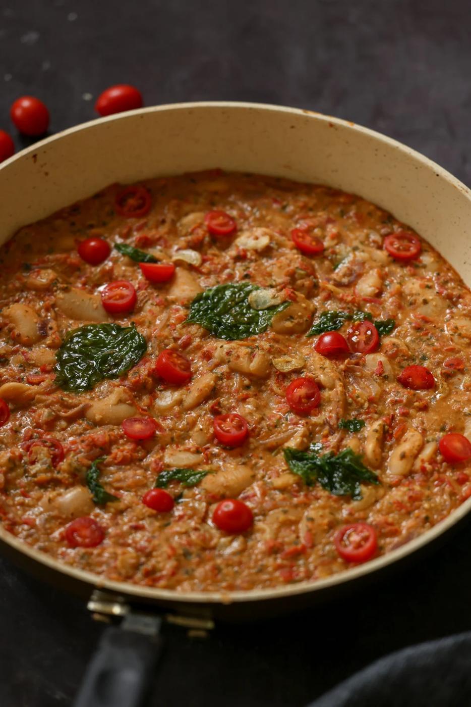 close-up of sicilian pesto sauce butter beans in the pan topped with crispy basil
