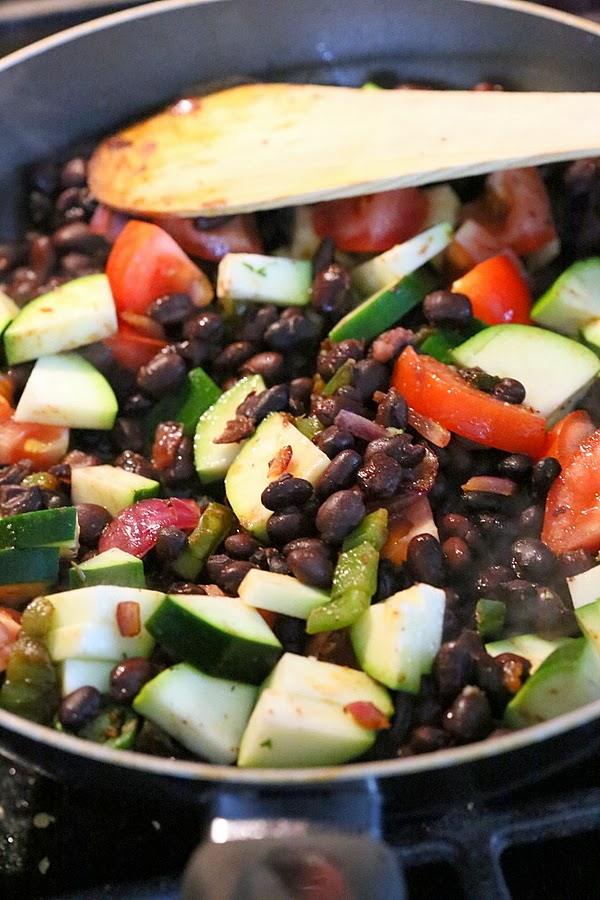 vegetarian filling for a vegan wrap recipe being sauteed in a black pan
