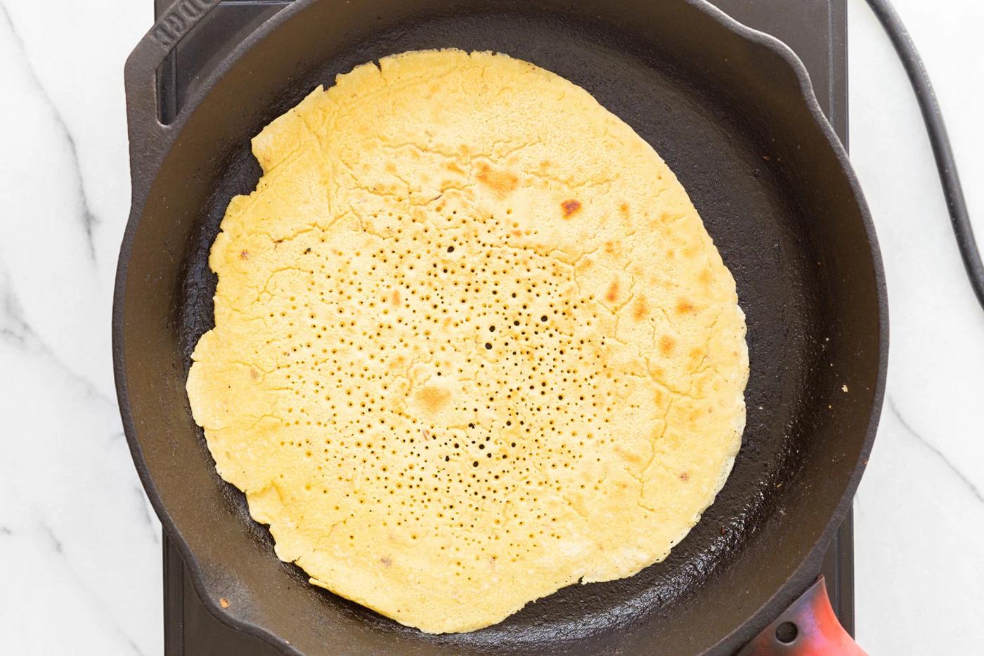 Socca cooking in cast iron skillet
