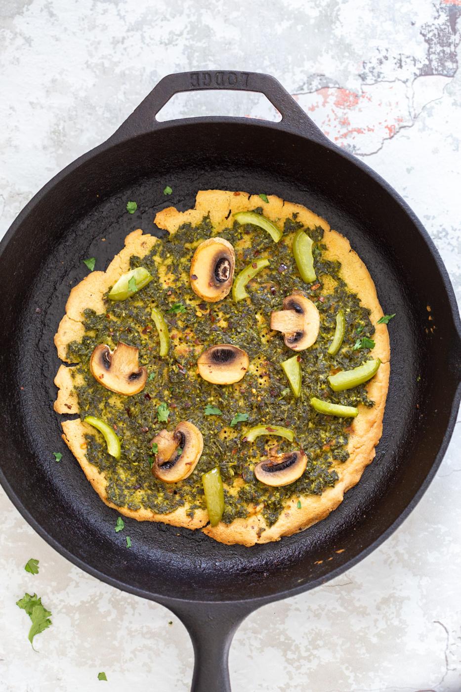 Socca Pizza with pesto and mushrooms on cast iron skillet