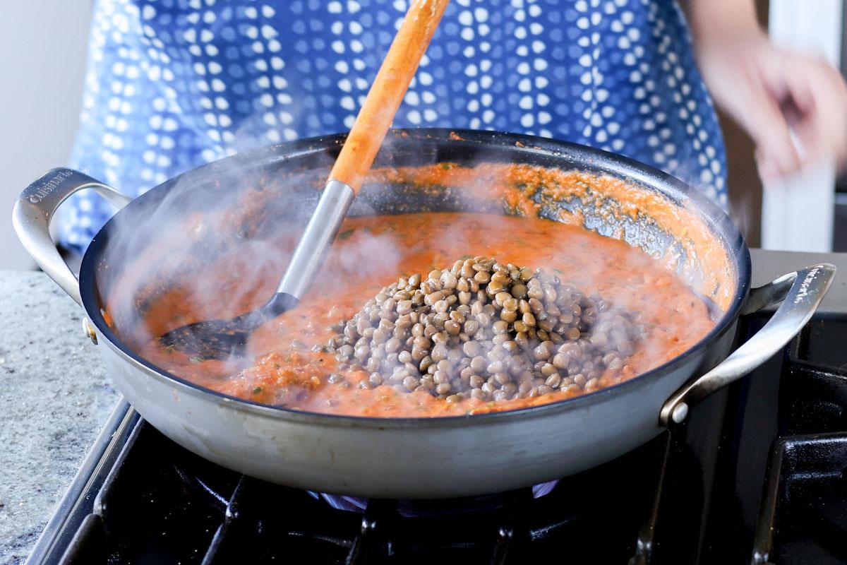 adding lentils to the pan of marry me sauce