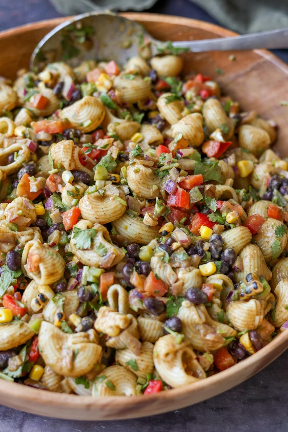 Pasta salad with black beans and corn in a wooden bowl.