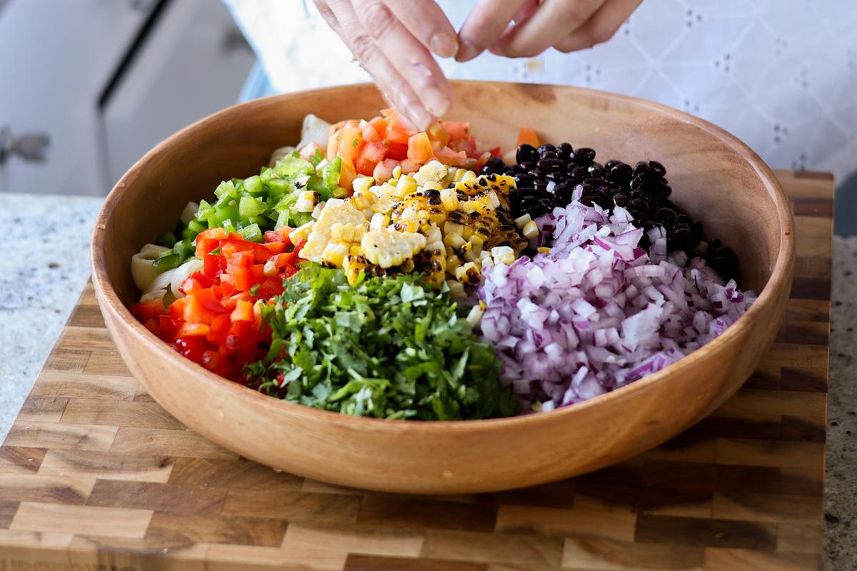 Corn added to the wooden bowl with the salad ingredients.