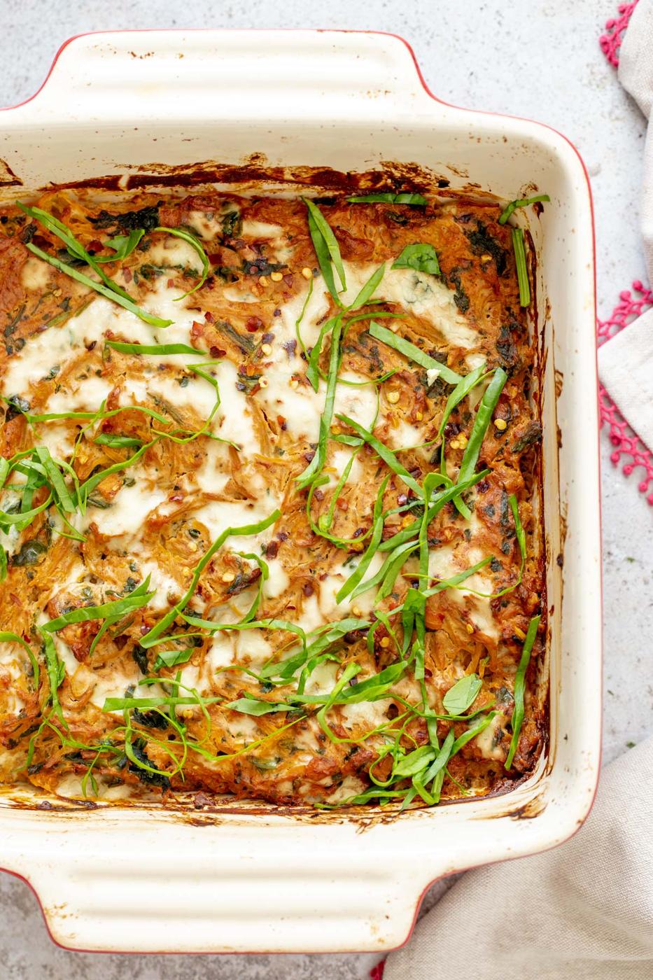 overhead shot of a casserole dish with vegan spaghetti squash bake sprinkled with fresh chopped basil