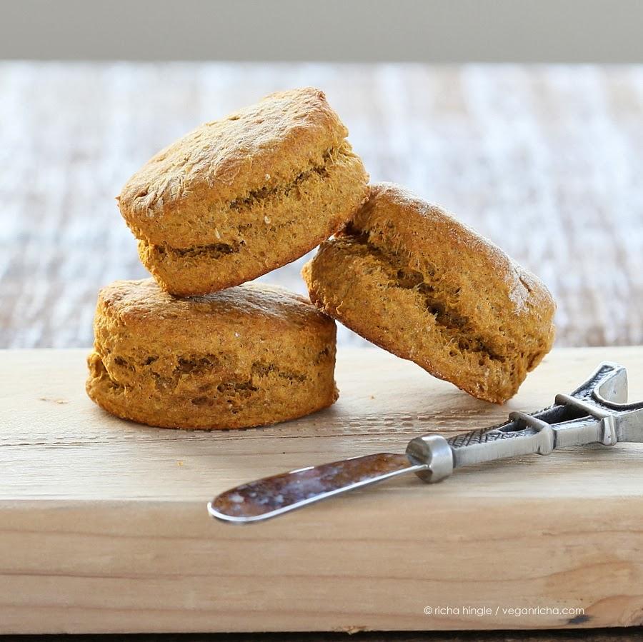 three vegan sweet potato biscuits made with spelt flour on a wooden board with a butter knife