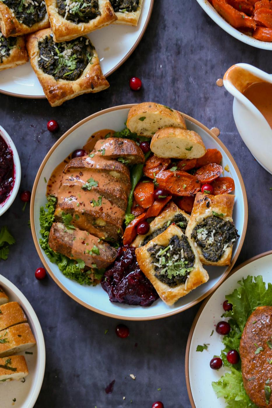 chickpea loaf with butter gravy on a plate with other Indian-style vegan Thanksgiving dishes