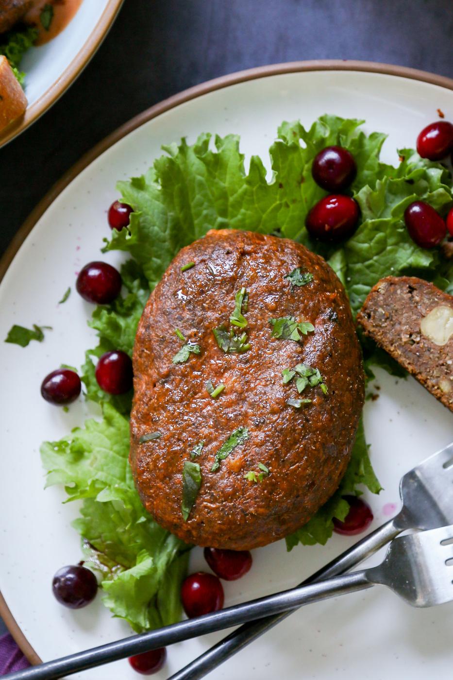 close-up of a chickpea loaf on a plate with lettuce and cranberries