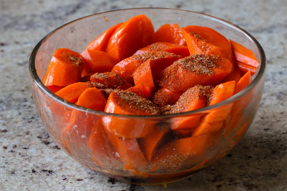 adding spices to the bowl of carrots