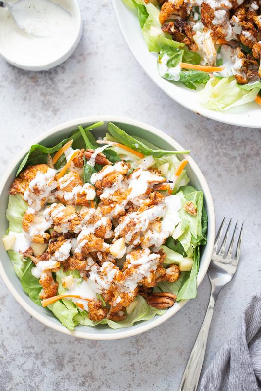 overhead shot of a bbq roasted cauliflower salad bowl drizzled with Vegan Ranch Dressing