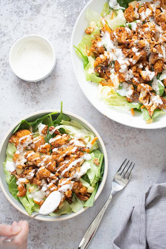 vegan bbq roasted cauliflower salad bowl being drizzled with vegan Ranch Dressing