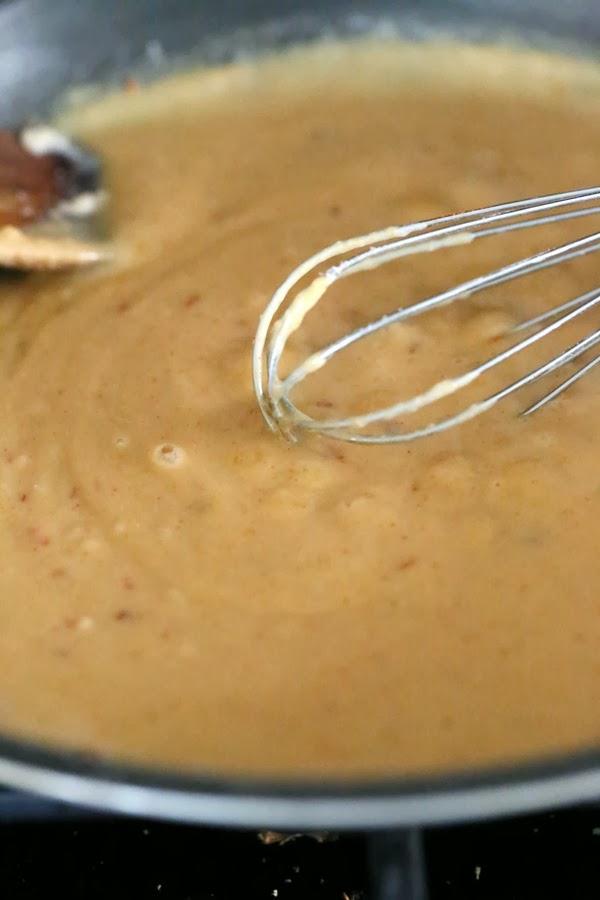 vegan mac and cheese sauce being stirred with a metal whisk in a saucepan
