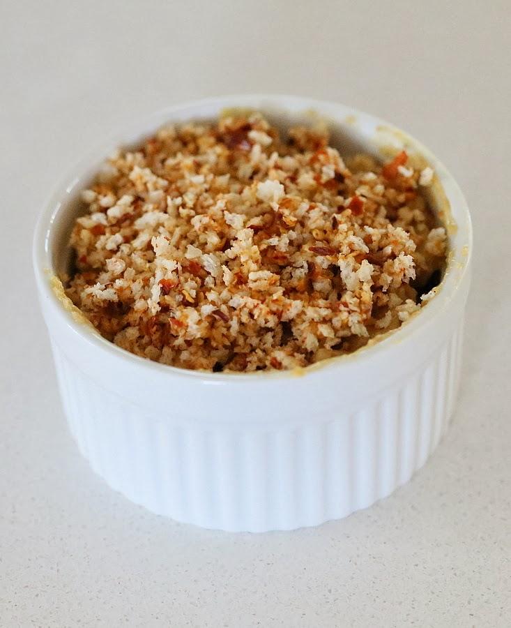 individual ramekins with dairy-free spicy mac and cheese being filled topped with vegan breadcrumbs