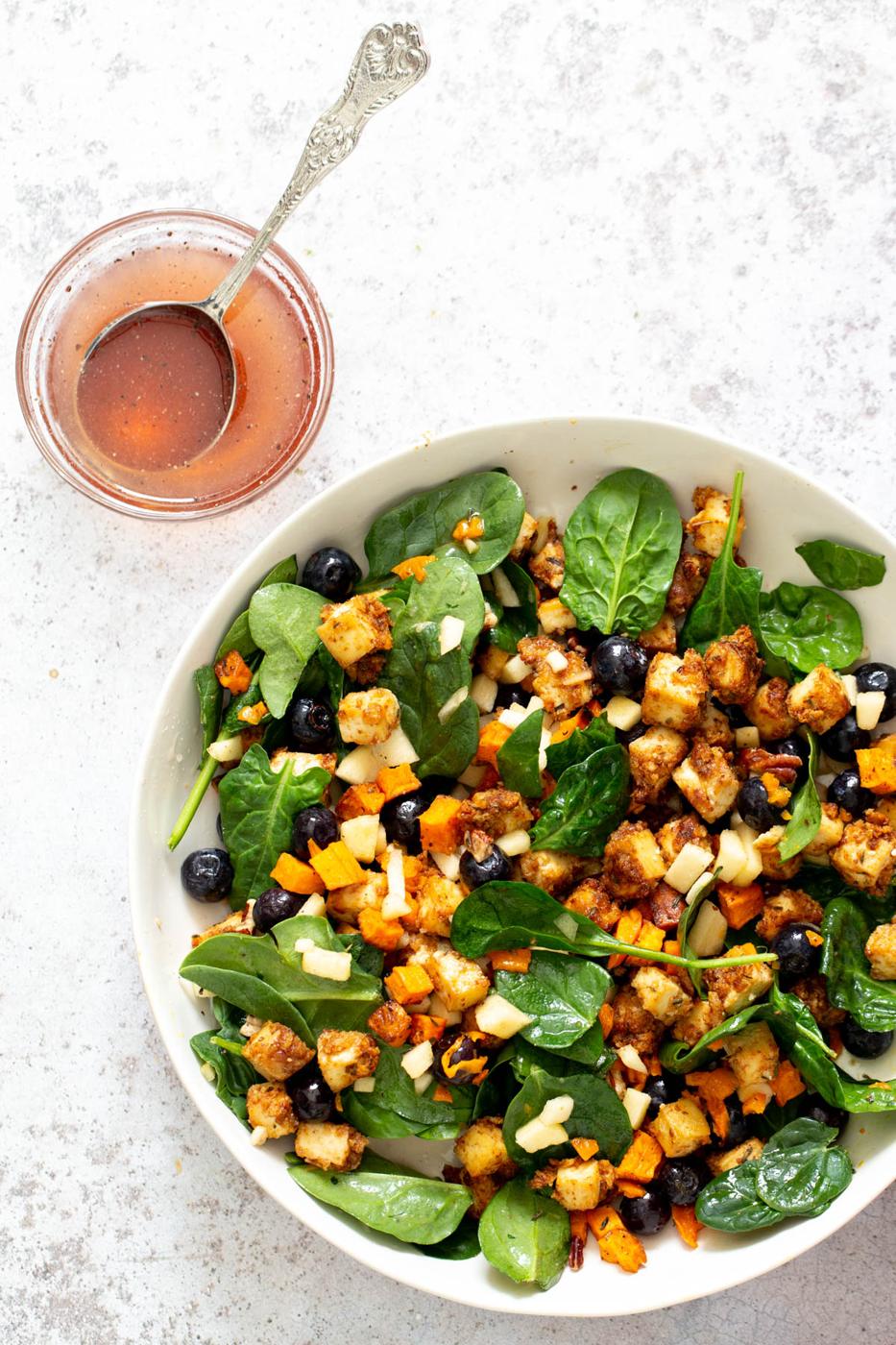 overhead shot of sweet potato tofu bowl with blueberries and apples served with a side of maple mustard dressing