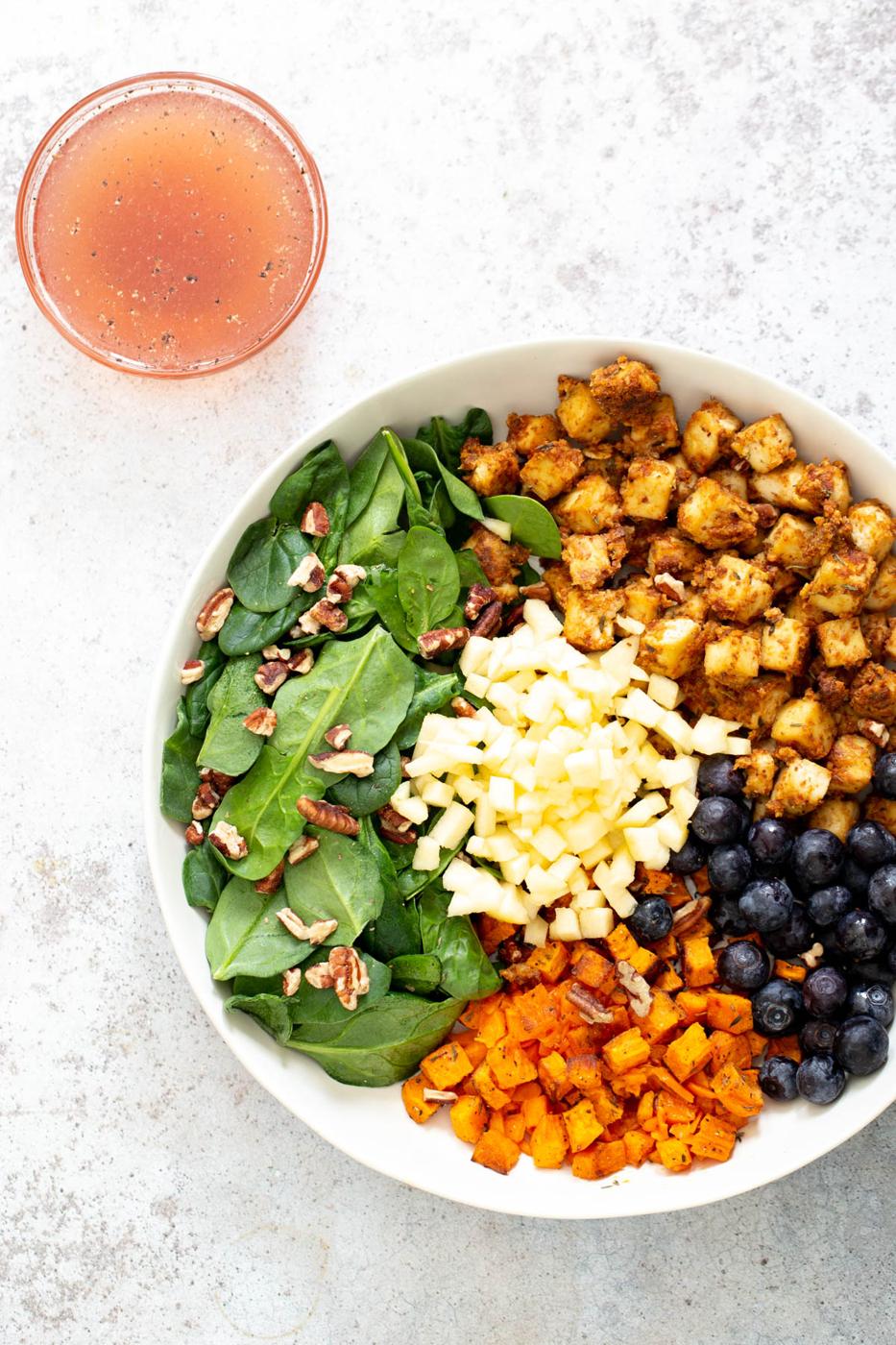 vegan sweet potato tofu bowl with a side of dressing