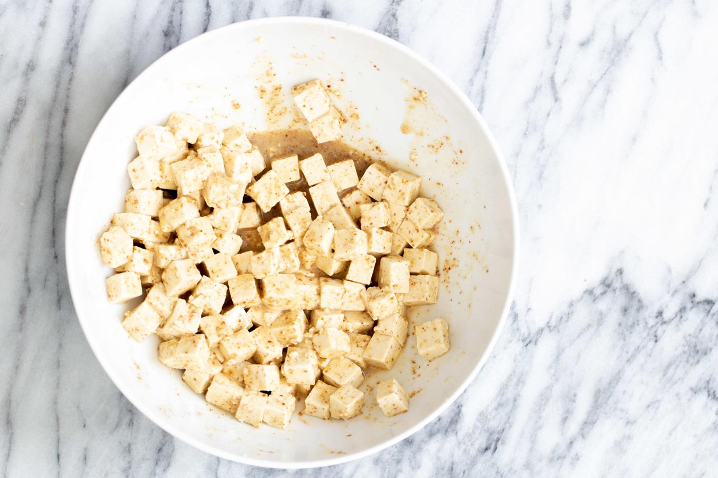 tofu mixed with marinade in a small white bowl