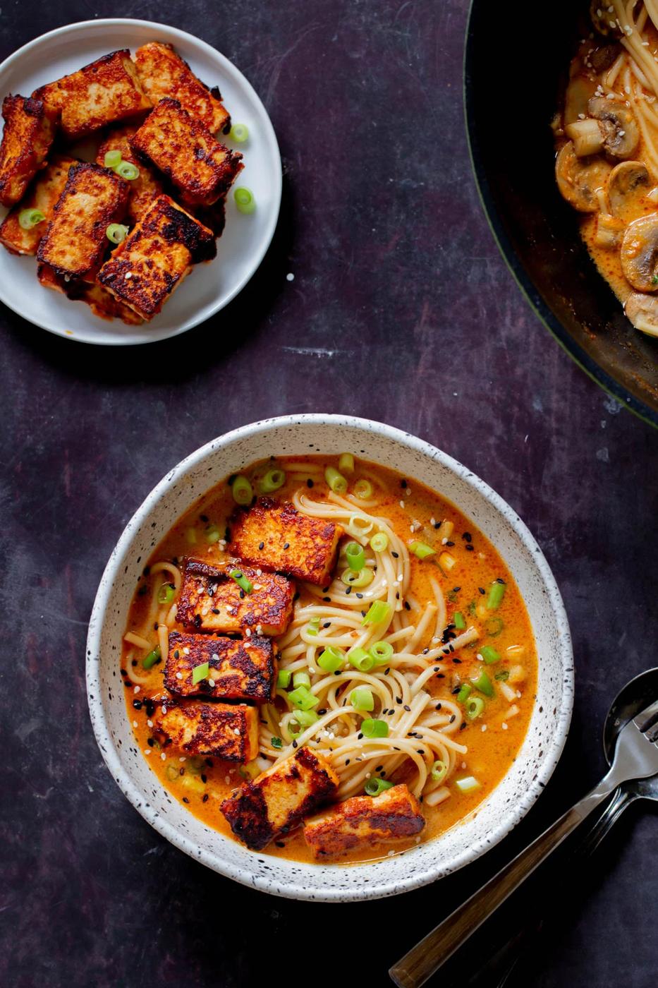 bowl of peanut gochujang ramen next to a plate of gochujang tofu
