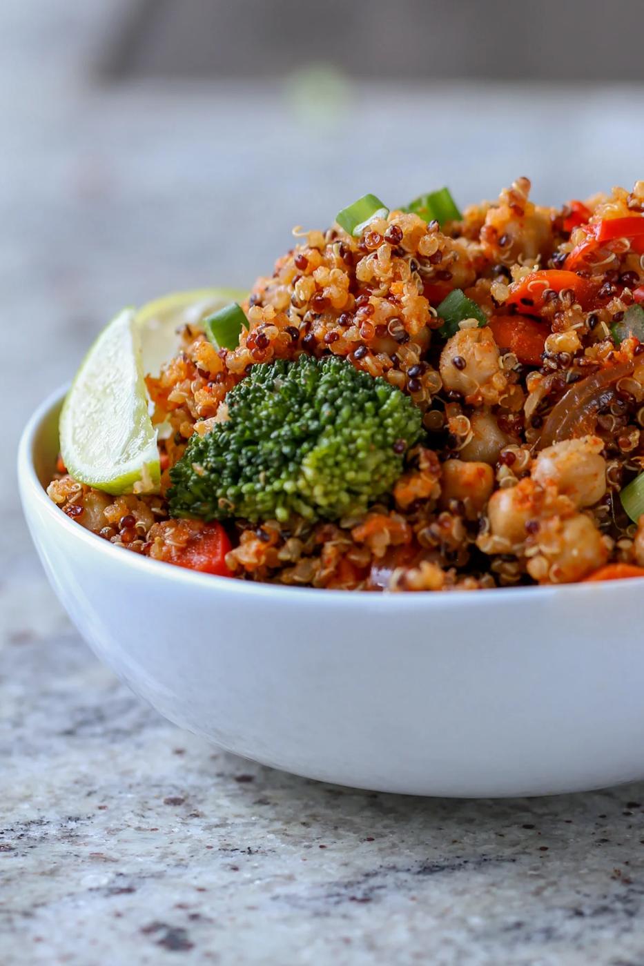 quinoa chickpea casserole in a bowl with lime wedge and green onion