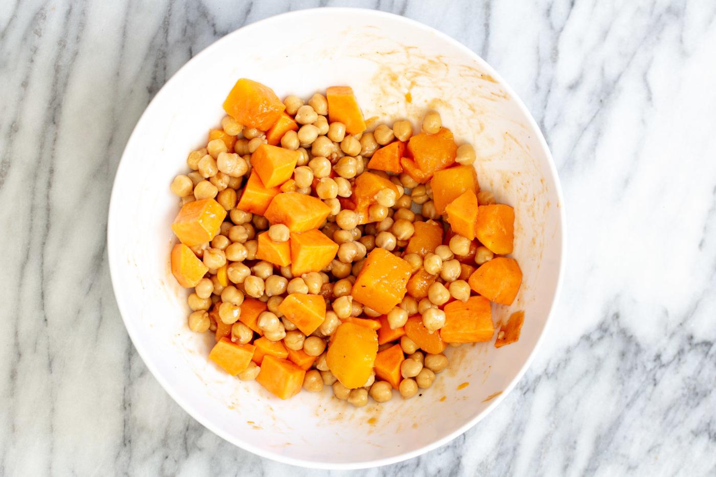 sweet potato and chickpeas being mixed in a bowl for salad recipe