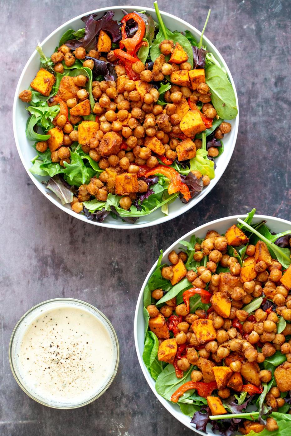 sweet potato chickpea salad in two bowls with a small side dish with tahini sauce