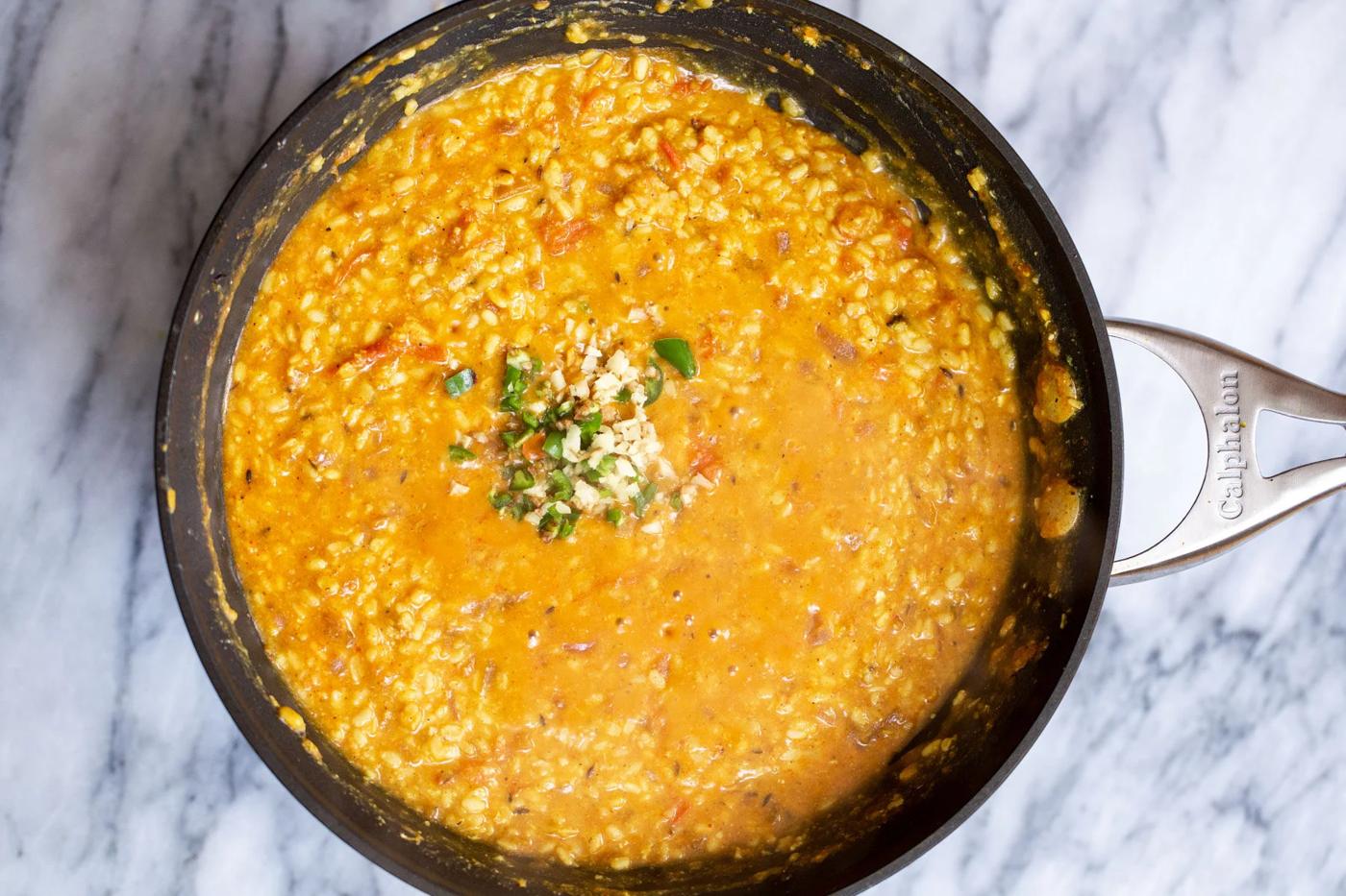 green chile and garlic being added to ural dal in a black skillet