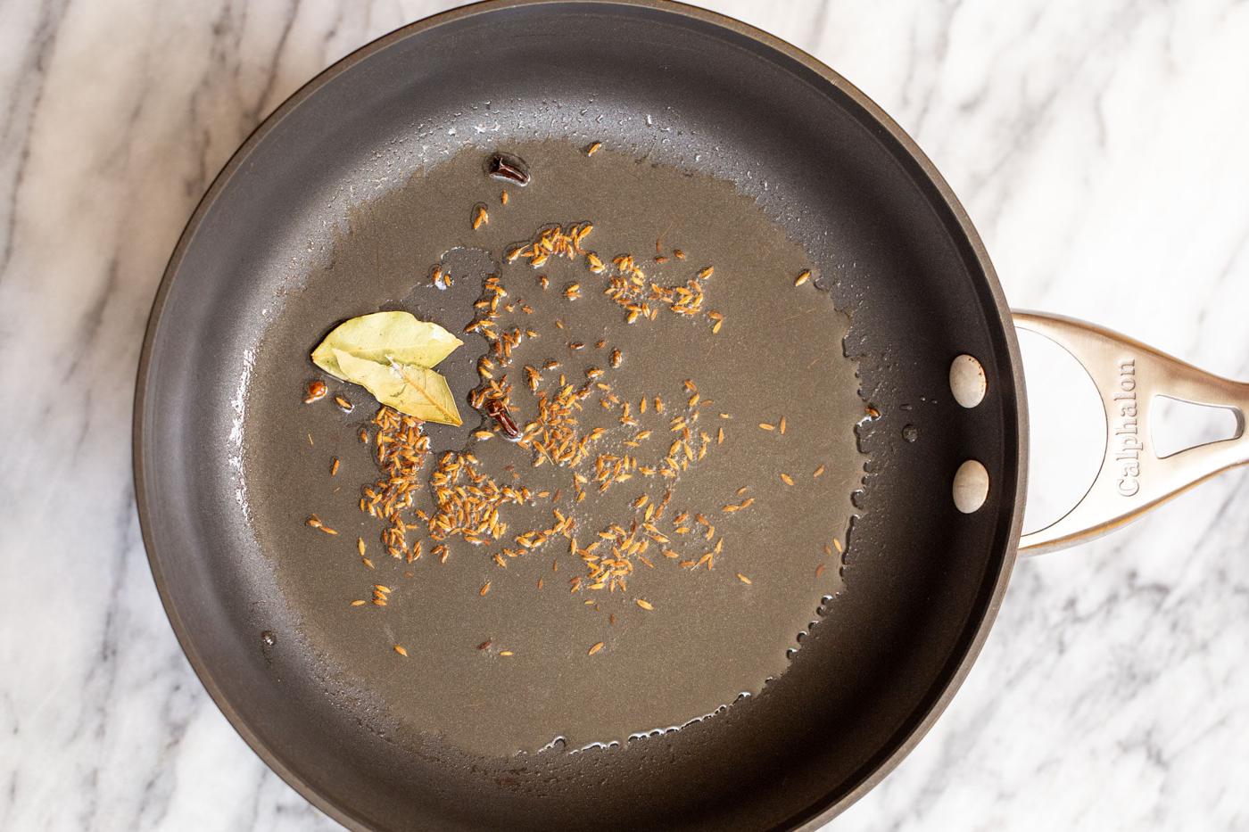 cumin, bay leaves and cloves being tempered in oil
